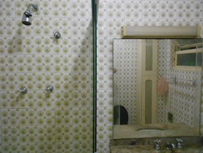 A bathroom with patterned tiles, a glass shower enclosure, and a mirror with a towel rack. - Gohouse - Belfort 502 (Rio de Janeiro)