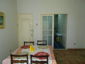 A dining area with a table set for two, chairs, a door, and a view into another room. - Gohouse - Belfort 502 (Rio de Janeiro)