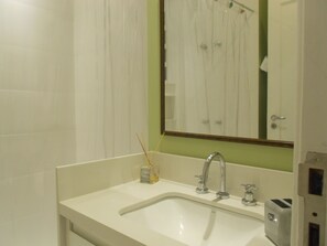 A bathroom with a white sink, a mirror, and a shower visible in the reflection. - Gohouse - Atlantica 702 B (Rio de Janeiro)