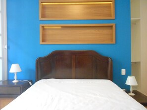 A hotel room with a wooden headboard, a blue wall, and two bedside lamps. - Gohouse - Atlantica 702 B (Rio de Janeiro)
