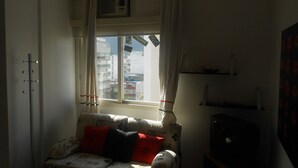 A room with a sofa, a TV, a window with curtains, and a ceiling fan. - Gohouse - Anibal 604 (Rio de Janeiro)