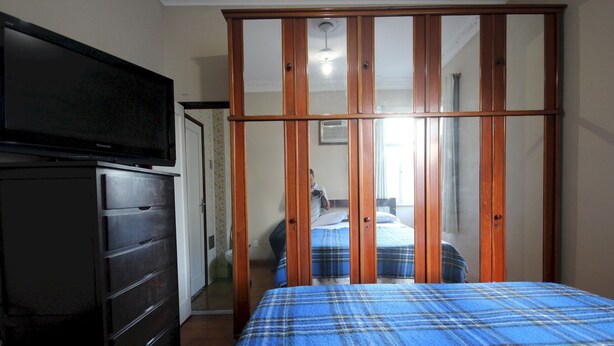 A bedroom with a bed, a dresser, a television, and a sliding door. - Gohouse - Botafogo 419 (Rio de Janeiro)