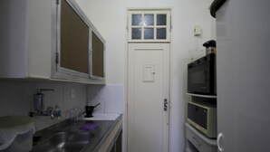 A compact kitchen with a sink, stove, and microwave. - Gohouse - Botafogo 419 (Rio de Janeiro)