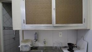 A kitchen with a stainless steel sink, a faucet, a bottle of dish soap, a purple cloth, and a black pot. - Gohouse - Botafogo 419 (Rio de Janeiro)