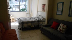 Un dormitorio con cama, sofá, ventana y radiador.