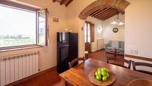 Une cuisine chaleureuse avec une table à manger, un réfrigérateur noir et une vue par la fenêtre.