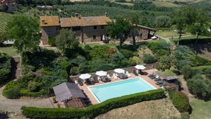 Une villa en pierre dotée d’une piscine, entourée d’une végétation luxuriante et de collines.