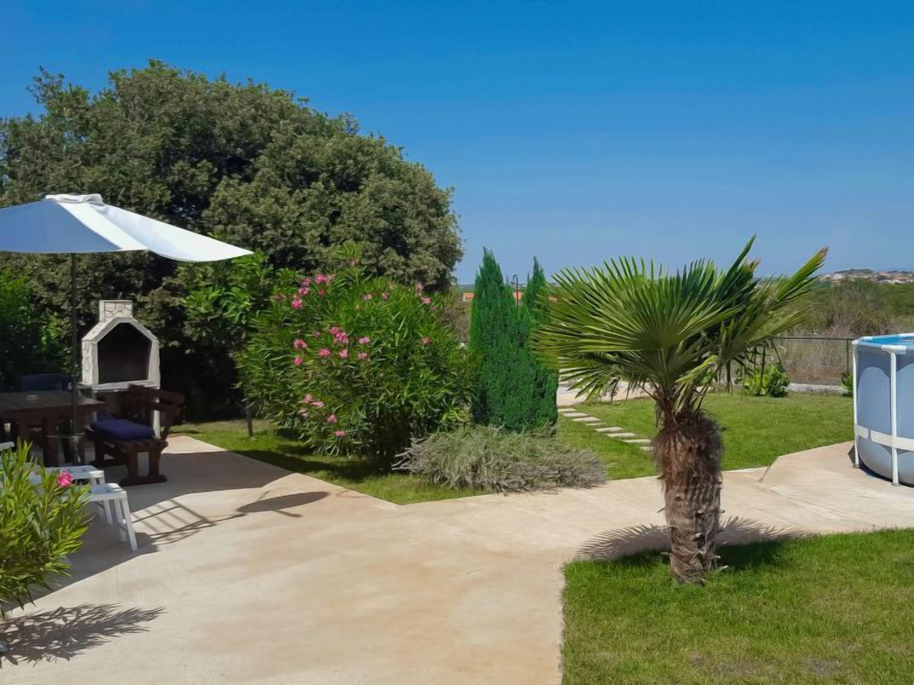 A patio area with a barbecue grill, outdoor seating, and a large umbrella.