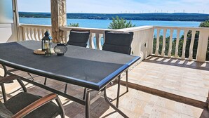 Una terraza con mesa y sillas, con vistas a un cuerpo de agua y un paisaje lejano.