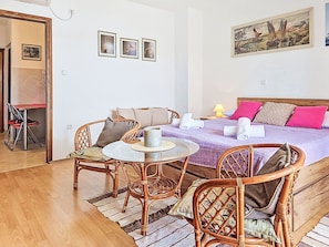 A room with a bed, a dining table, wicker chairs, a small round table, and a painting on the wall. - Apartment Matal by Interhome (Novigrad (Zadar))