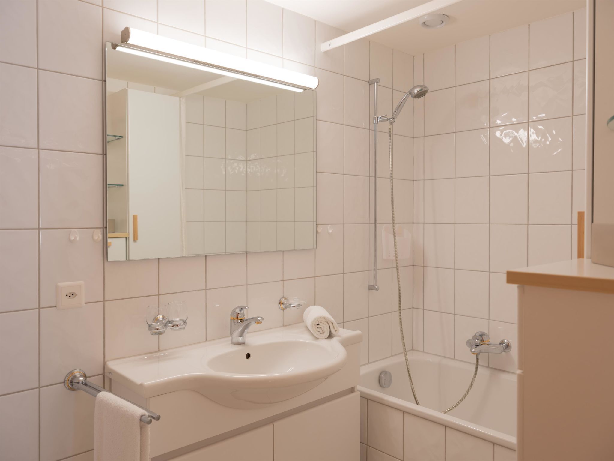 Une salle de bain avec un lavabo blanc, un miroir et une douche.
