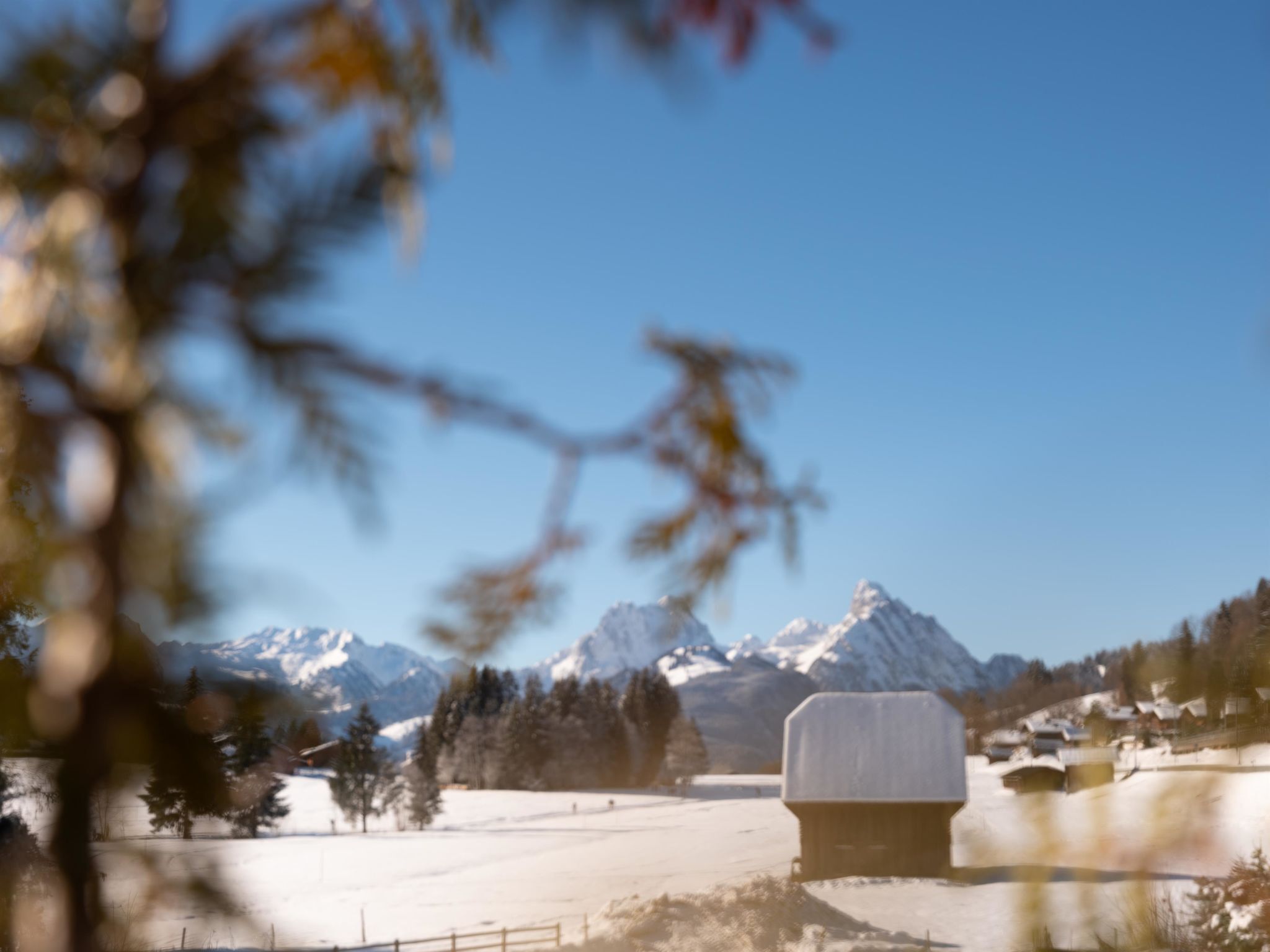 A snow-covered mountain landscape with a wooden cabin in the foreground.