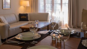 A dining area with a table set for two, a sofa, and a lamp in a well-lit room with large windows. - Fichte (Marija) by Interhome (Saanenmöser)