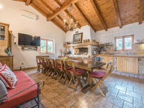 Un comedor acogedor con una mesa y sillas de madera, un televisor montado en la pared y una cocina con chimenea de piedra.