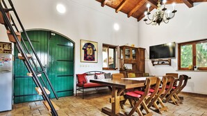 A dining area with a wooden table and chairs, a green door, a framed jersey, and a television on the wall. - Malu Sun II by Interhome (Brodarica)