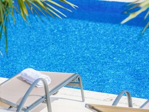 Zona de piscina con una silla de descanso y una toalla.