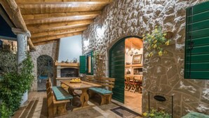 An outdoor patio with stone walls, wooden furniture, and a fireplace. - Malu Sun II by Interhome (Brodarica)