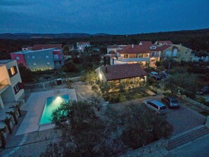 Zona residencial con casas, una piscina y coches aparcados.