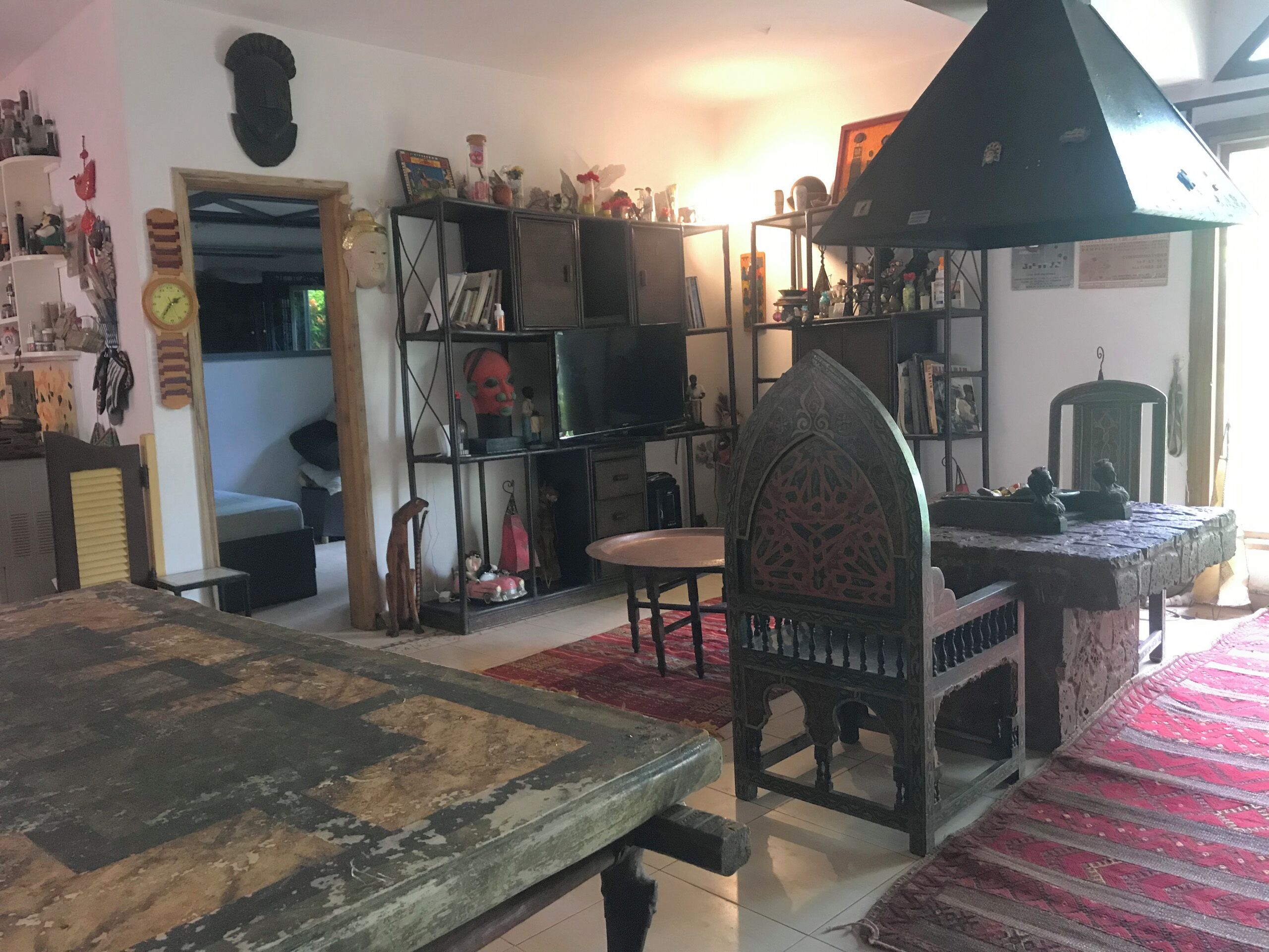 A living room with a sofa, a coffee table, and a bookshelf filled with various items.