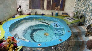 Un jacuzzi con mosaicos y un mural decorativo en la pared de fondo.
