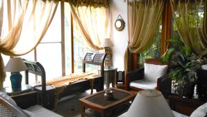 Una sala de estar acogedora con sofá, sillones, una mesa de centro y un piano.