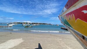 Una playa con barcos y un bote colorido amarrado a la derecha.