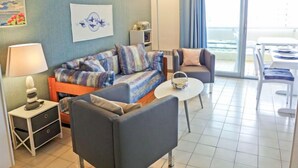 Un salon moderne comprenant un canapé, des fauteuils, une table basse et un coin repas avec une table et des chaises.