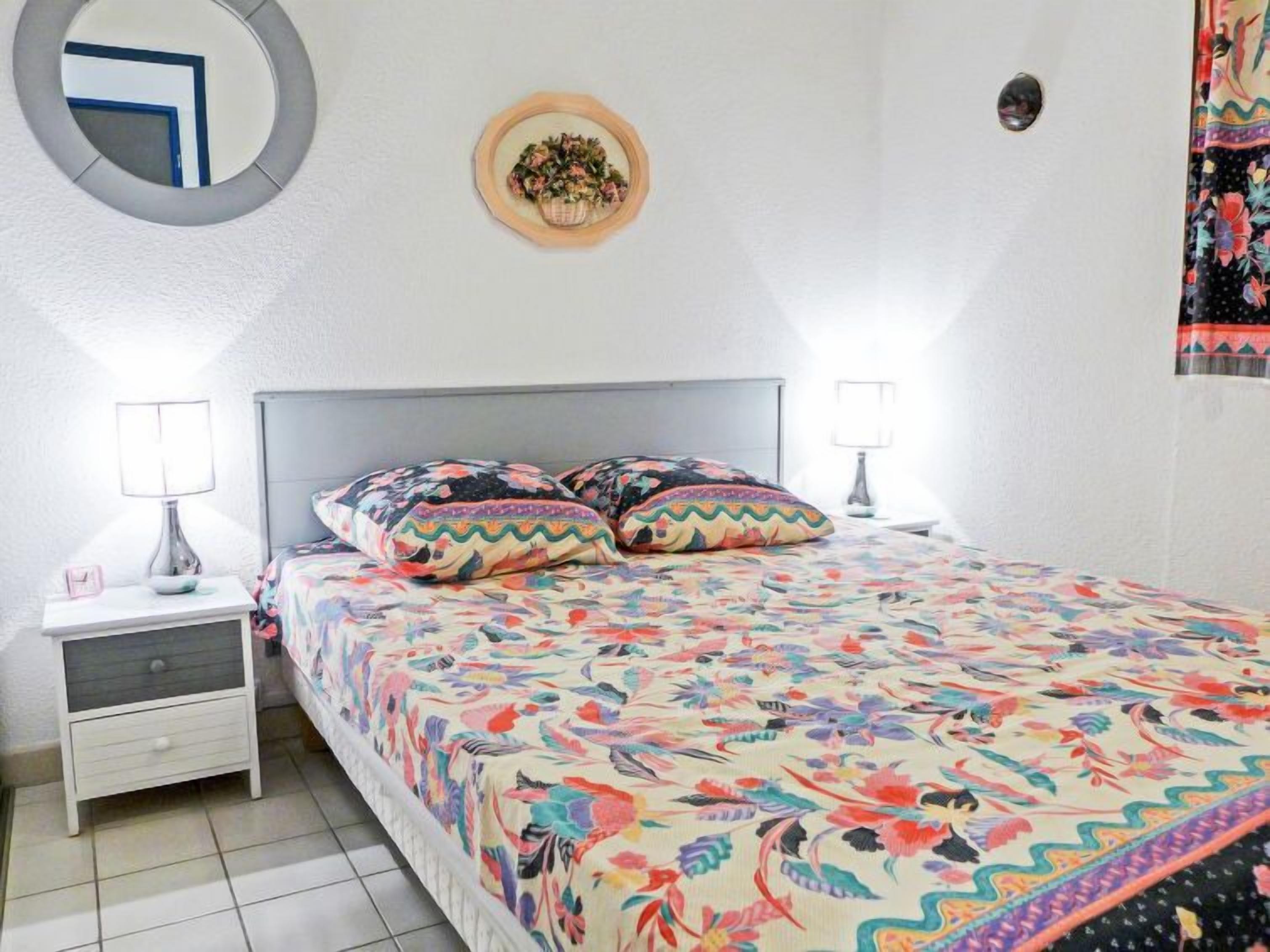 Camera da letto con un letto, due comodini, uno specchio e una lampada a parete.