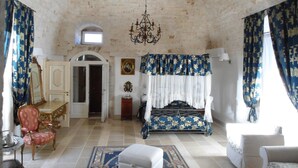 A bedroom with a bed, a chair, a desk, and a chandelier. - Parco dei Manieri (Conversano)