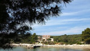 A coastal property with a house near a clear water body, surrounded by greenery and rocky terrain. - Vacation home Jure by Interhome (Pašman/Neviđane)