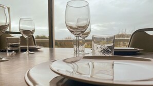 Een eettafel met borden, glazen en bestek, met uitzicht op de natuur.