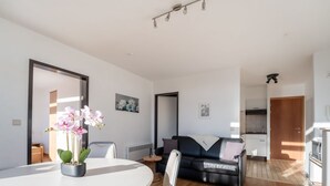 Een moderne woonkamer met een eettafel, bank en keukenhoek.