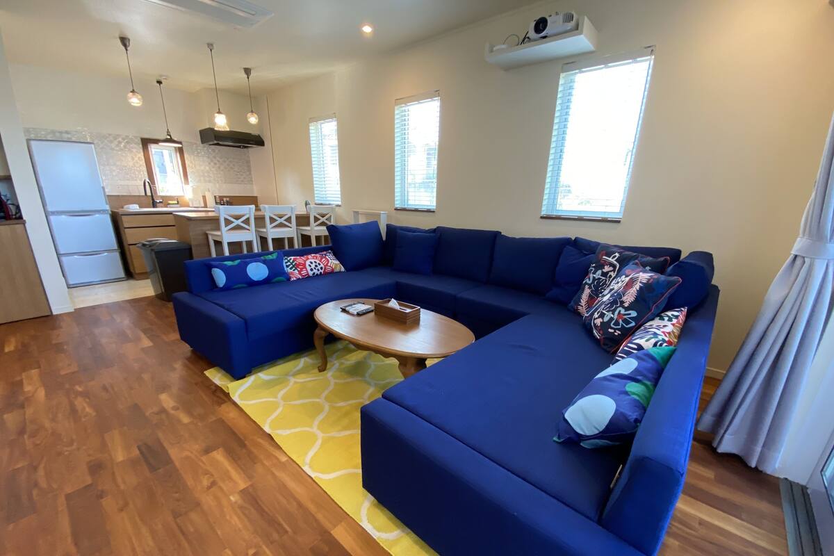 Uma sala de estar moderna com um sofá seccional, uma mesa de centro de madeira e um tapete amarelo estampado.