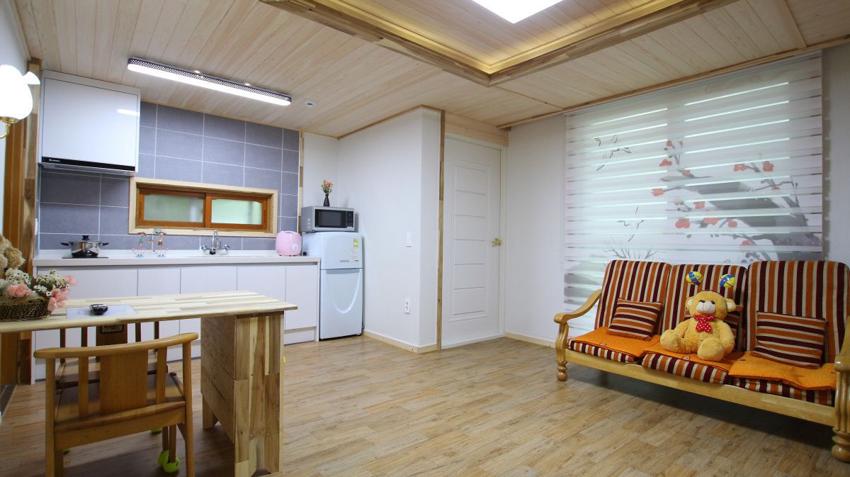 Un espacio habitable pequeño con kitchenette, comedor y sofá con un peluche.