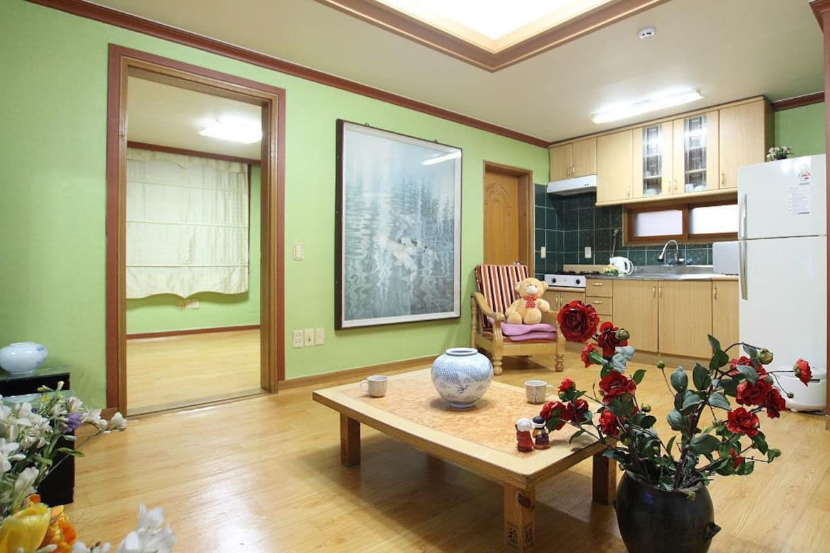A compact living space with a dining area, kitchen, and a large framed picture on the wall.