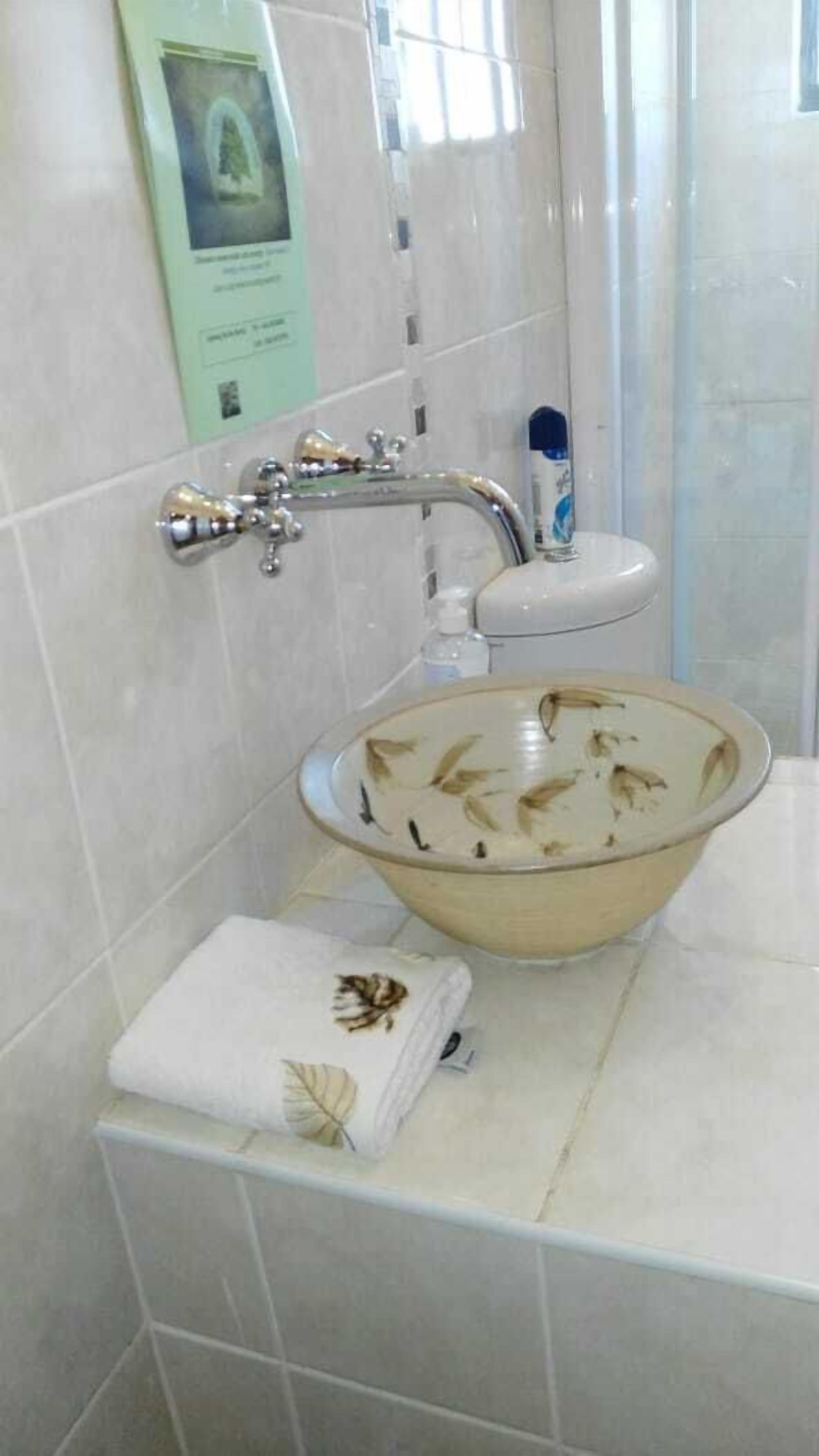 A bathroom with a white sink, a towel, and a bottle of hand soap.
