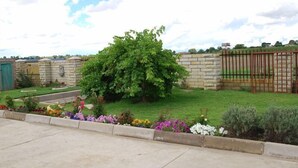 A garden with a stone wall, a metal gate, and a variety of colorful flowers. - Lapeng Habo Bantu (Mafeteng)