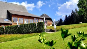 A two-story building with a sloped roof, large windows, and a well-maintained lawn.