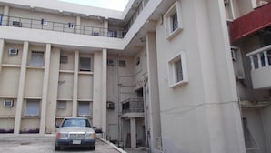 A multi-story building with a car parked in front. - Rendezvous Hotel (Abuja)