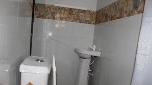 A bathroom with a toilet, sink, and a trash bin. - Rendezvous Hotel (Abuja)