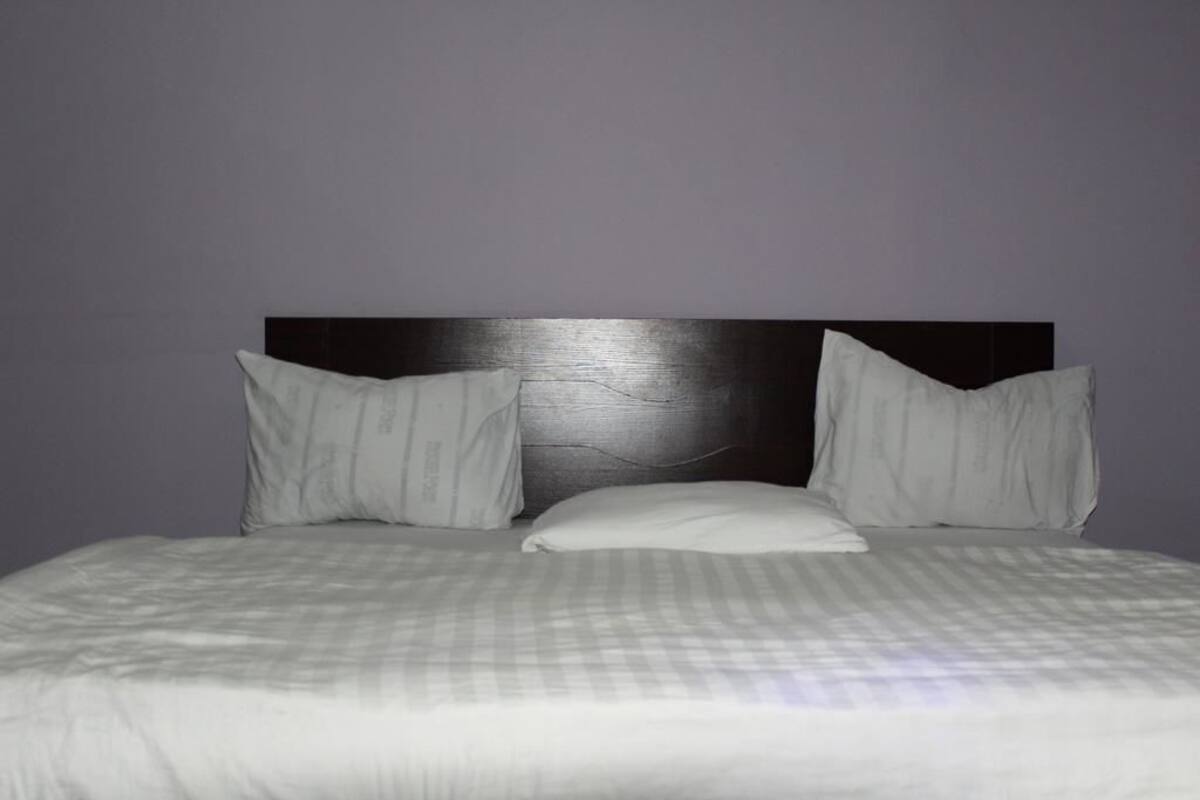A bed with a headboard, two pillows, and a checkered bedspread.