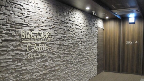 Pared de textura de piedra con un letrero que dice "BIZCORT CABIN SUSHIKO".