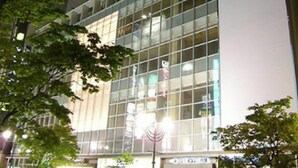 Un edificio moderno con fachada de vidrio y señalización para ASIL Sapporo.