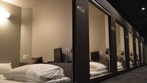 Habitación de hotel con cama, escritorio con computadora y espejo que refleja la habitación.