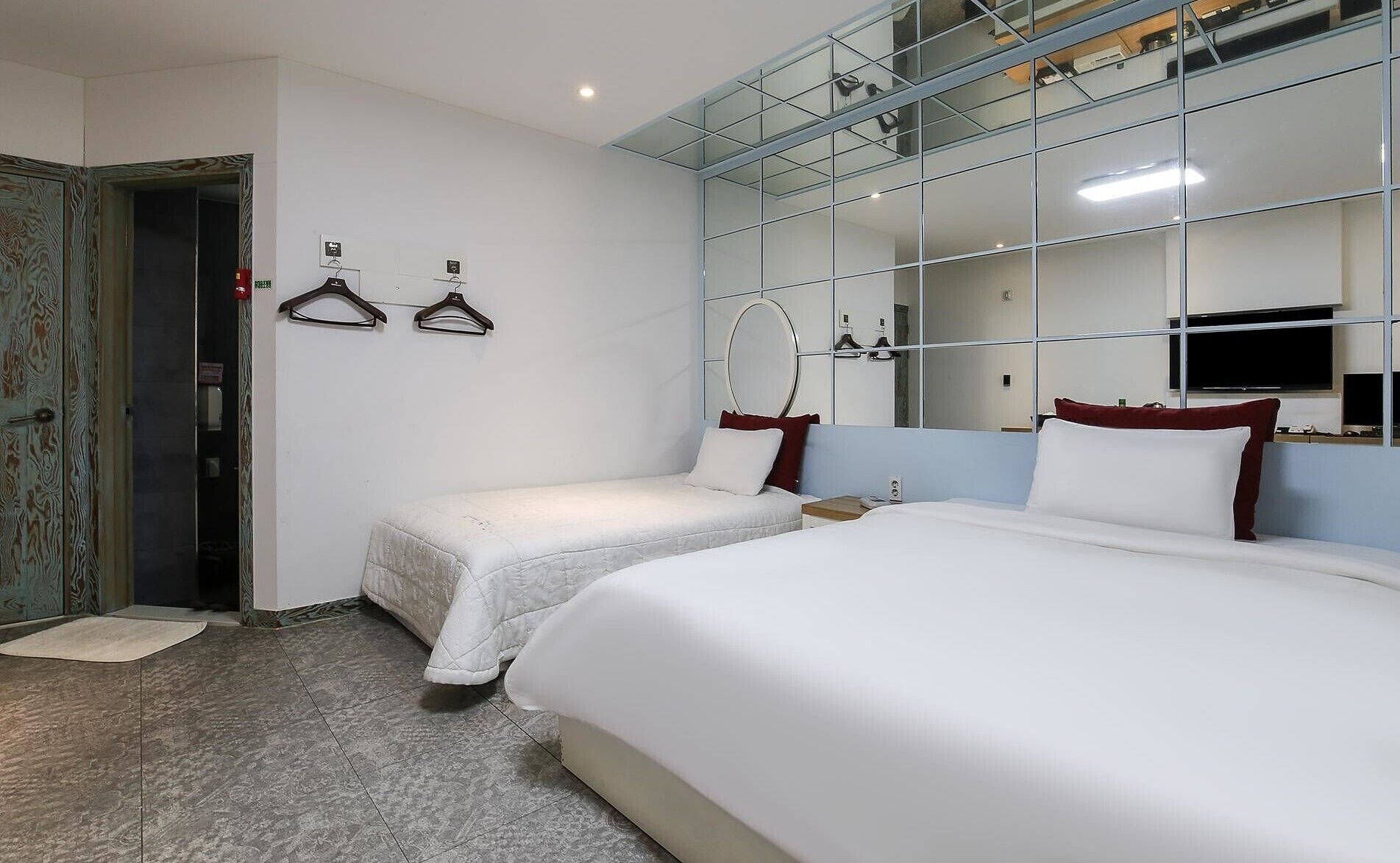 A hotel room with two single beds, a large mirror, and a wardrobe with a mirror.