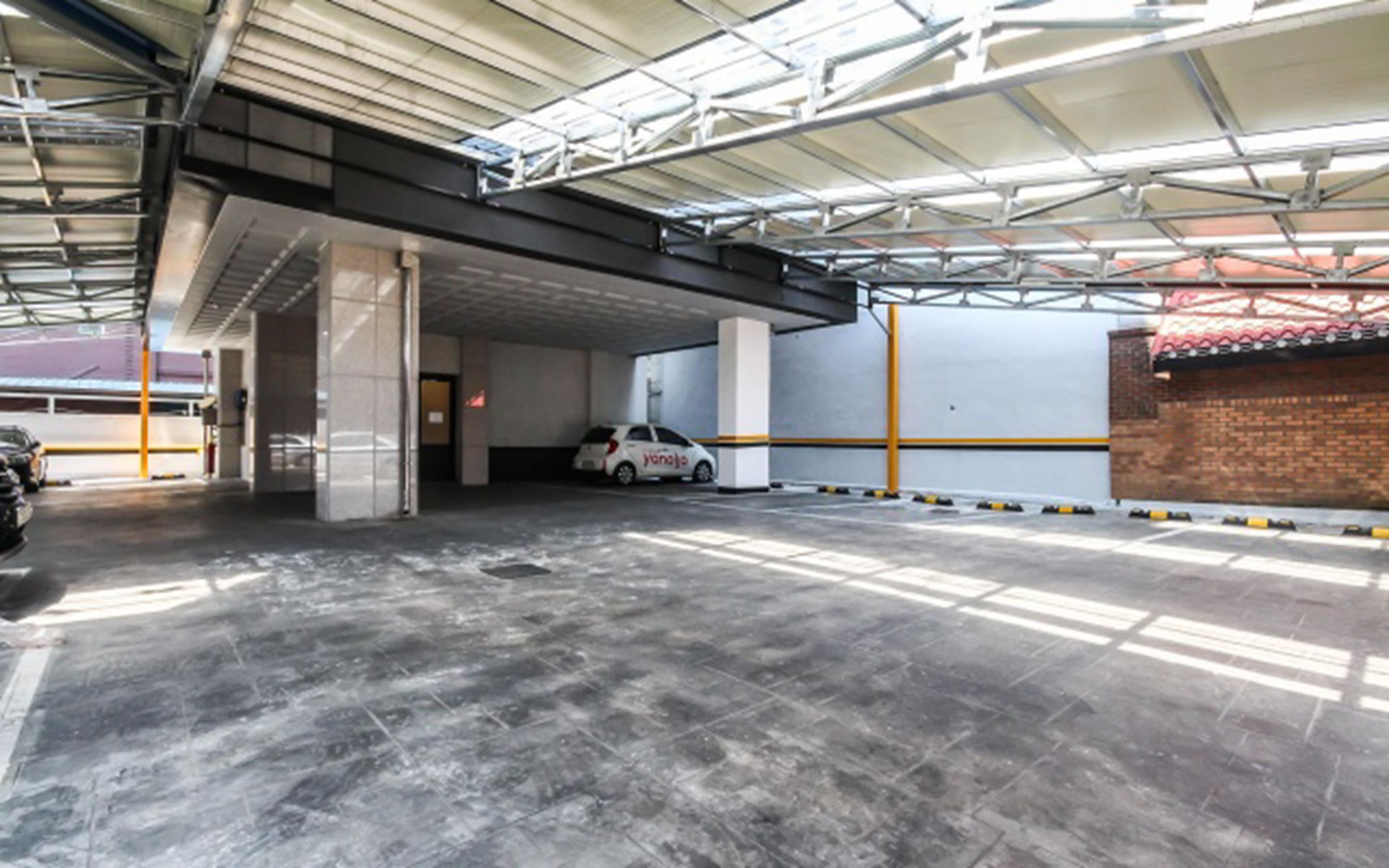 An indoor parking garage with a white car parked in a bay.