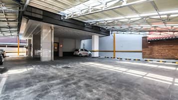 An indoor parking garage with a white car parked in a bay.