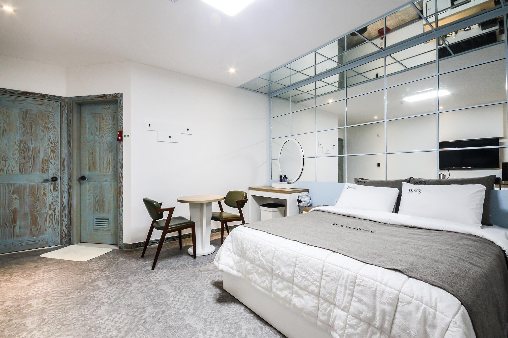 Una habitación de hotel moderna con una cama grande, un escritorio, una silla y un espejo.