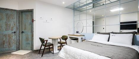 Una habitación de hotel moderna con una cama grande, un escritorio, una silla y un espejo.