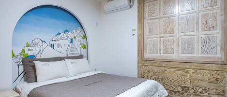 A bedroom with a bed, a wall-mounted air conditioner, a wooden panel wall, and a large circular window.